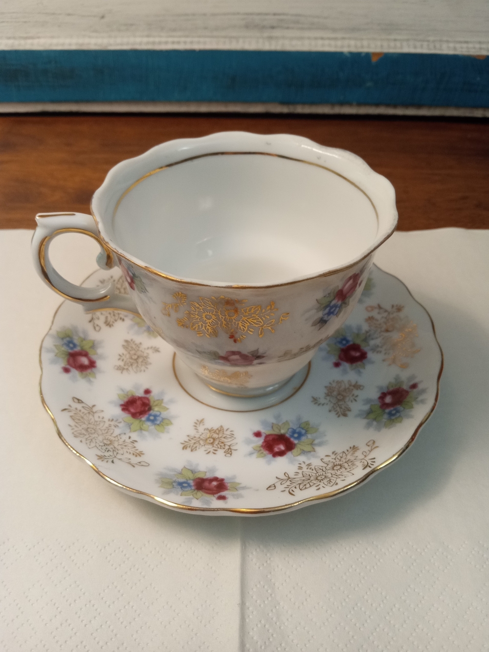 Elegant White Porcelain Teacup and Saucer with Red Floral Accents and Gold Trim